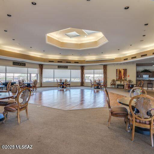 carpeted dining space with a wealth of natural light and a raised ceiling