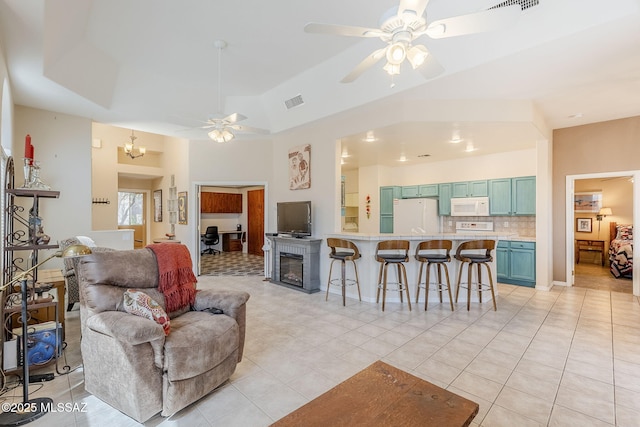 living room featuring visible vents, ceiling fan with notable chandelier, a fireplace, light tile patterned floors, and lofted ceiling