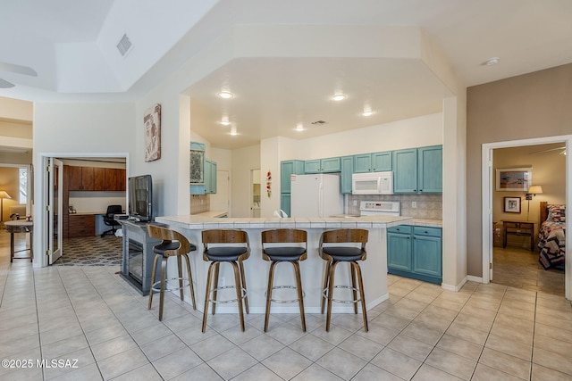 kitchen featuring tile countertops, visible vents, white appliances, and a breakfast bar area