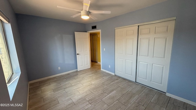 unfurnished bedroom featuring visible vents, baseboards, wood finish floors, multiple windows, and a closet