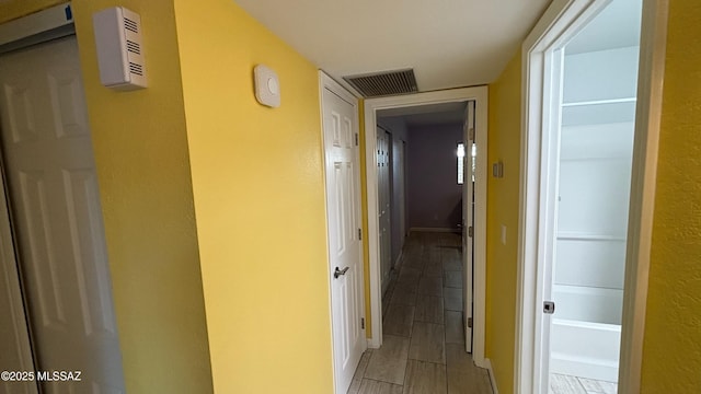 corridor featuring baseboards, visible vents, and wood tiled floor