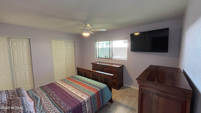 bedroom featuring a ceiling fan, light wood-style floors, baseboards, and two closets