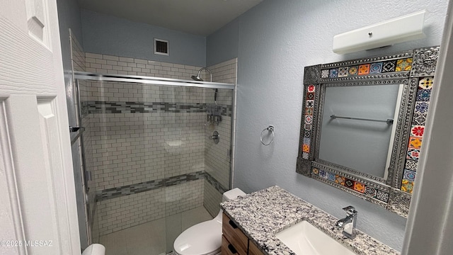 bathroom with visible vents, toilet, a stall shower, a textured wall, and vanity