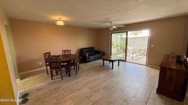 dining space with a textured ceiling, baseboards, and ceiling fan