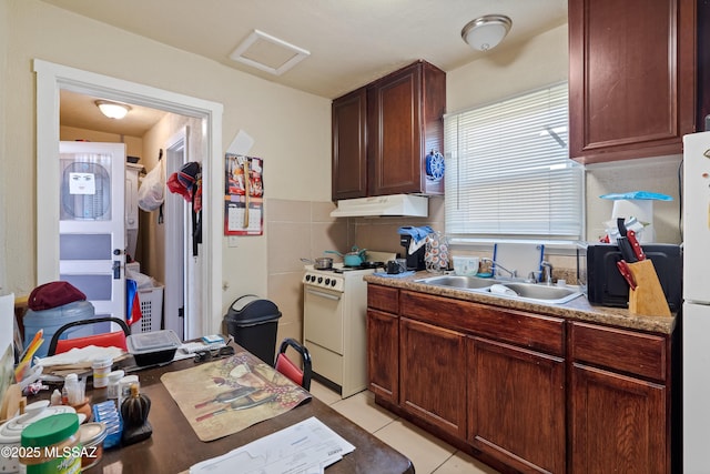 kitchen featuring light tile patterned floors, light countertops, a sink, white appliances, and under cabinet range hood