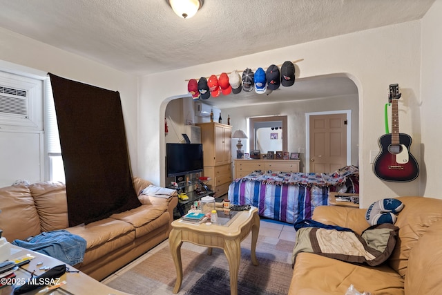 living room featuring arched walkways, light tile patterned flooring, and a textured ceiling