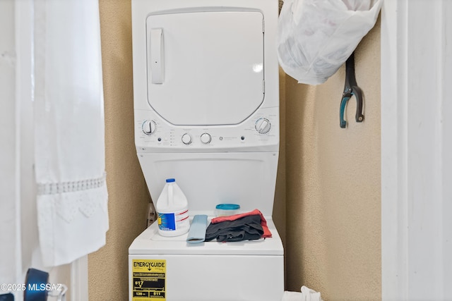 laundry room featuring stacked washer and dryer, laundry area, and a textured wall