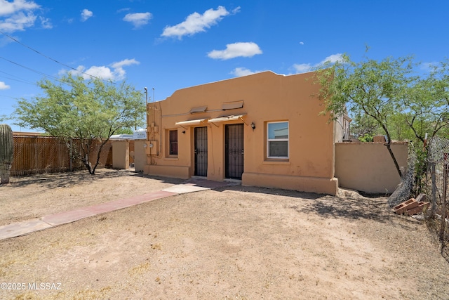 view of front facade with fence and stucco siding