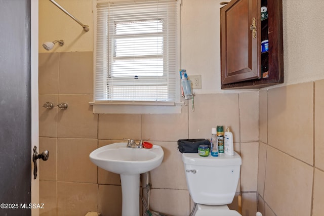 bathroom featuring toilet and tile walls