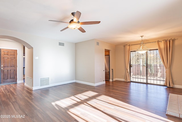 spare room with wood finished floors, arched walkways, ceiling fan, and visible vents