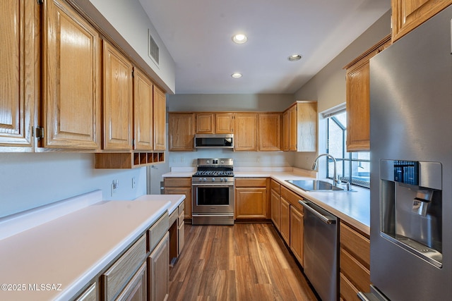 kitchen with light countertops, recessed lighting, stainless steel appliances, a sink, and dark wood-style floors