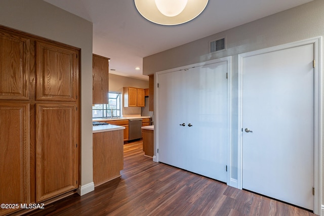 kitchen featuring light countertops, dark wood-style flooring, a sink, visible vents, and dishwasher
