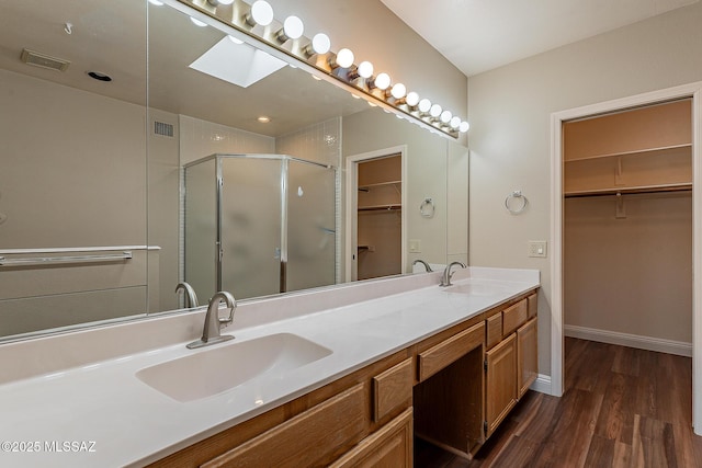 full bathroom featuring a stall shower, visible vents, wood finished floors, and a sink