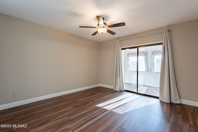 spare room featuring baseboards, ceiling fan, and dark wood-style flooring
