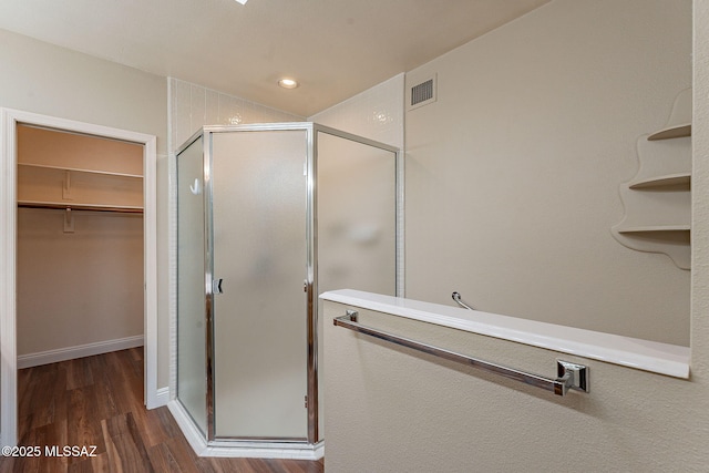 full bath with a shower stall, visible vents, wood finished floors, and a walk in closet