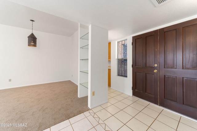 foyer entrance with light tile patterned floors, visible vents, light carpet, and baseboards