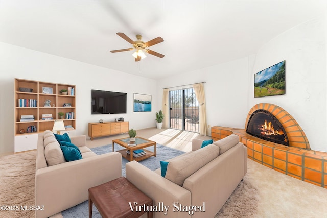 living area featuring a warm lit fireplace, ceiling fan, and carpet floors