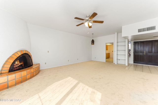 unfurnished living room featuring light carpet, visible vents, a fireplace, and a ceiling fan