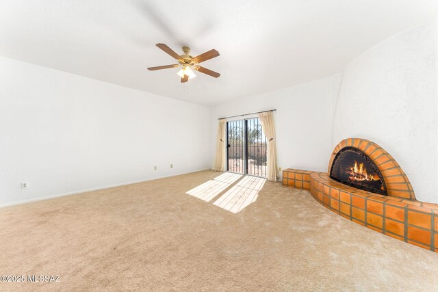 unfurnished living room with a tiled fireplace, a ceiling fan, and carpet