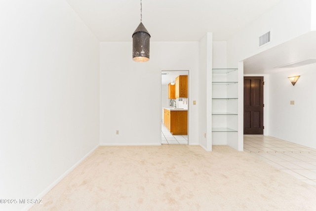 unfurnished room featuring light tile patterned floors, light colored carpet, visible vents, and a sink