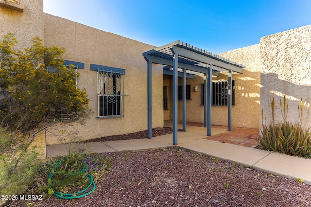 exterior space with stucco siding, a pergola, and a patio