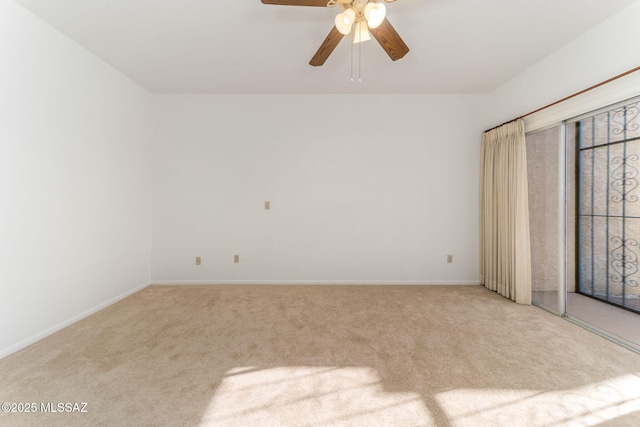 carpeted spare room featuring baseboards and ceiling fan