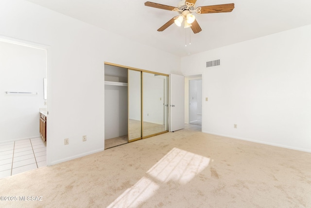 unfurnished bedroom featuring light tile patterned flooring, visible vents, light colored carpet, and ensuite bath