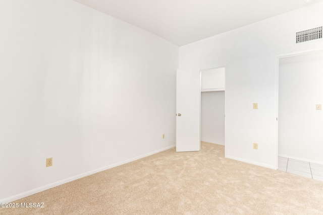 empty room featuring visible vents, light carpet, and baseboards