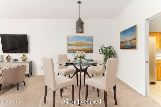 dining space featuring light carpet and baseboards