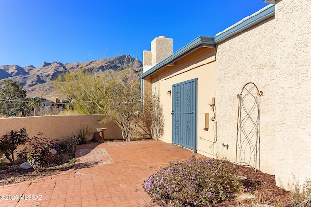 property entrance featuring stucco siding, fence, a mountain view, a chimney, and a patio area