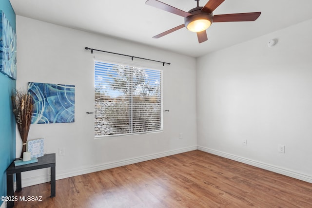 unfurnished room with a ceiling fan, baseboards, and wood finished floors