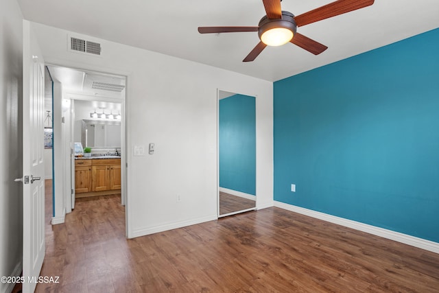 unfurnished bedroom with visible vents, ceiling fan, baseboards, wood finished floors, and a closet