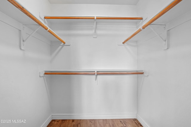 walk in closet with wood finished floors