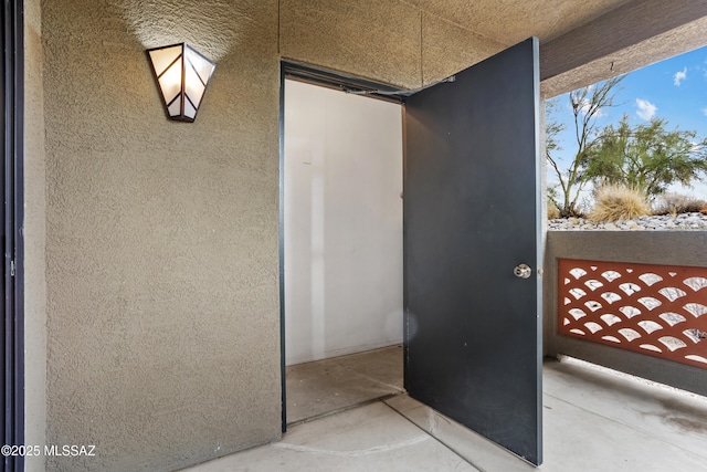 view of exterior entry with stucco siding and a balcony