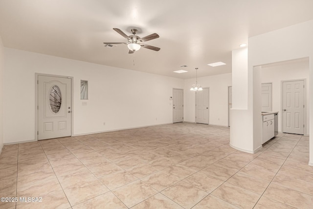 empty room with ceiling fan with notable chandelier, visible vents, and baseboards