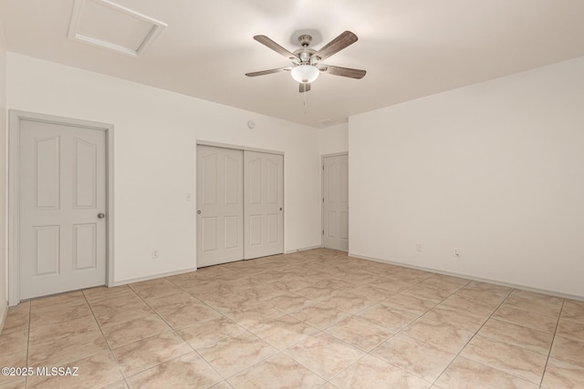 unfurnished bedroom featuring attic access, baseboards, a closet, and a ceiling fan