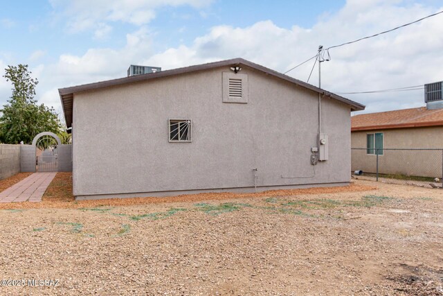 rear view of property with stucco siding, a gate, and fence