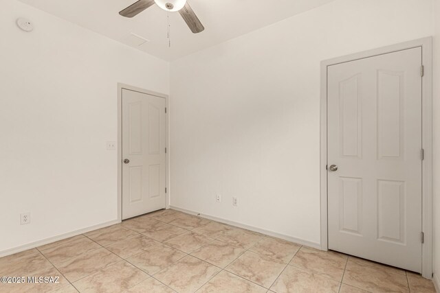 spare room with baseboards, light tile patterned floors, and a ceiling fan
