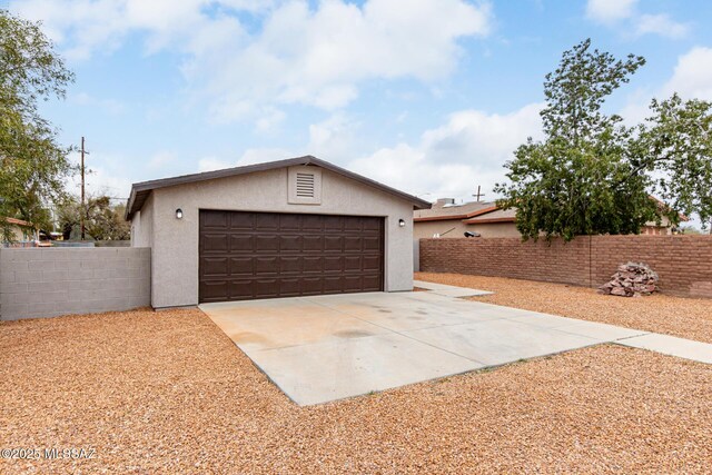 garage with fence and concrete driveway