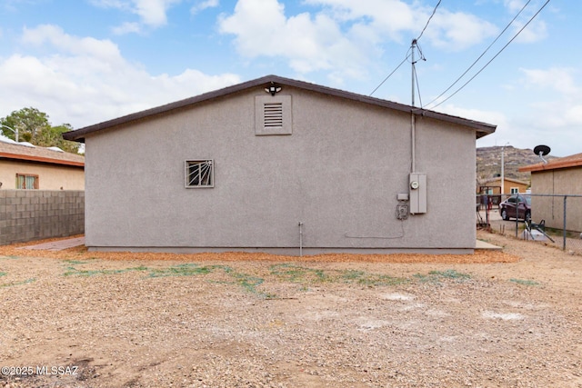 rear view of house with stucco siding and fence