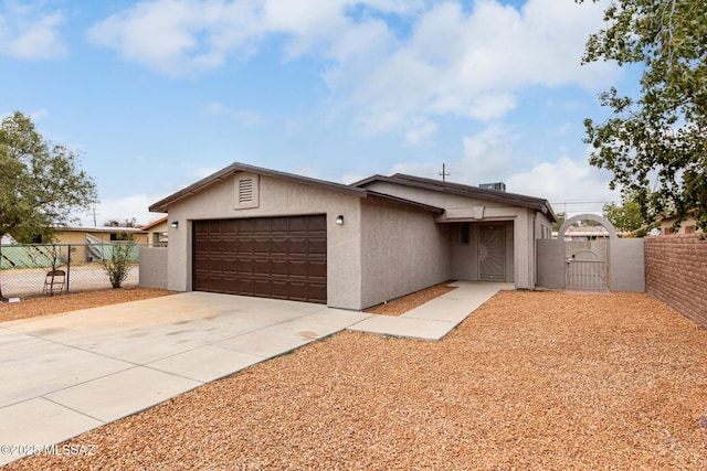 view of front of home featuring concrete driveway, stucco siding, fence, a gate, and a garage