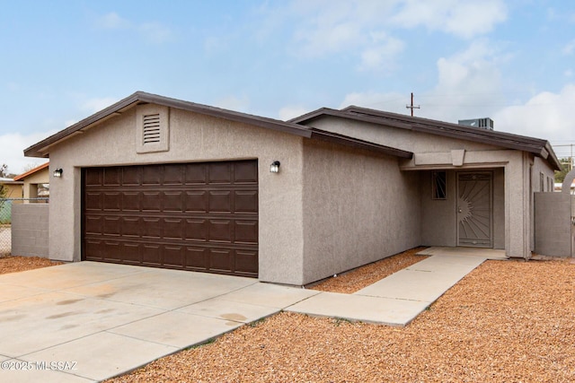 ranch-style house featuring stucco siding, an attached garage, fence, and concrete driveway