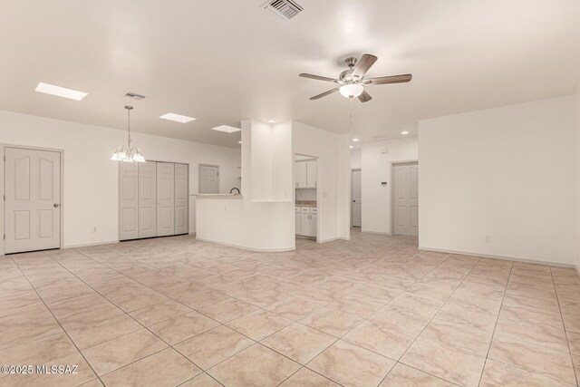 unfurnished living room featuring ceiling fan with notable chandelier, baseboards, and visible vents