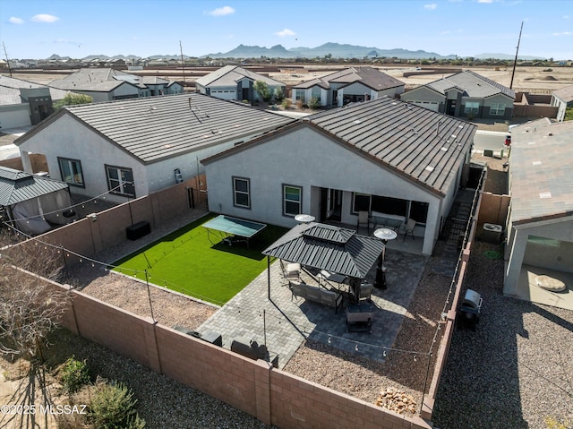 rear view of property with stucco siding, a fenced backyard, a mountain view, a residential view, and a patio area