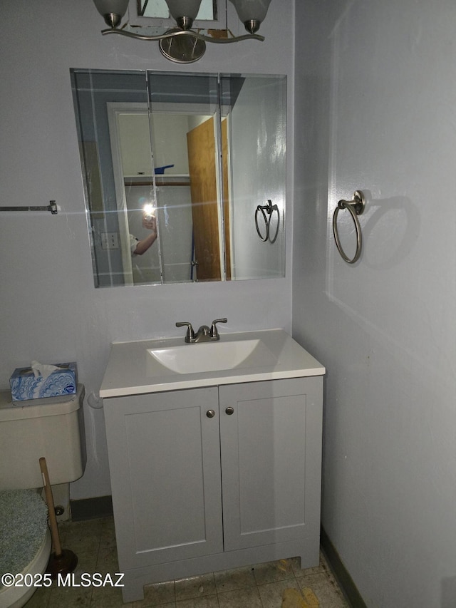 bathroom featuring toilet, baseboards, and vanity