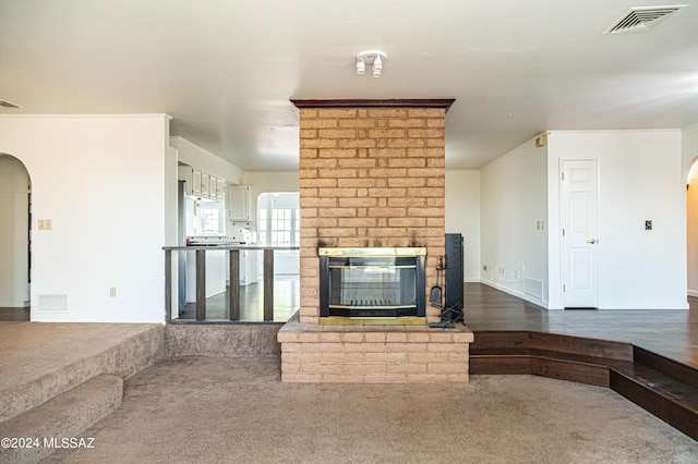 unfurnished living room with a brick fireplace, visible vents, and arched walkways