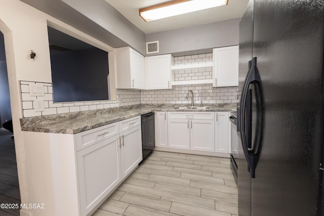 kitchen featuring visible vents, white cabinets, decorative backsplash, black appliances, and a sink