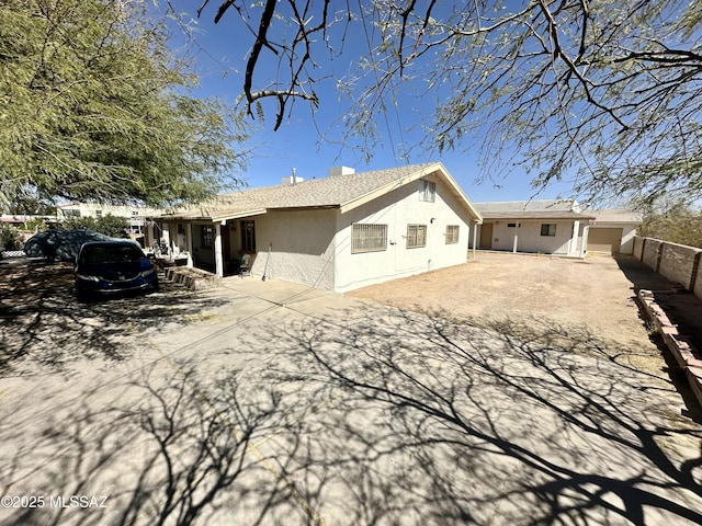 rear view of house with fence, a patio, and stucco siding