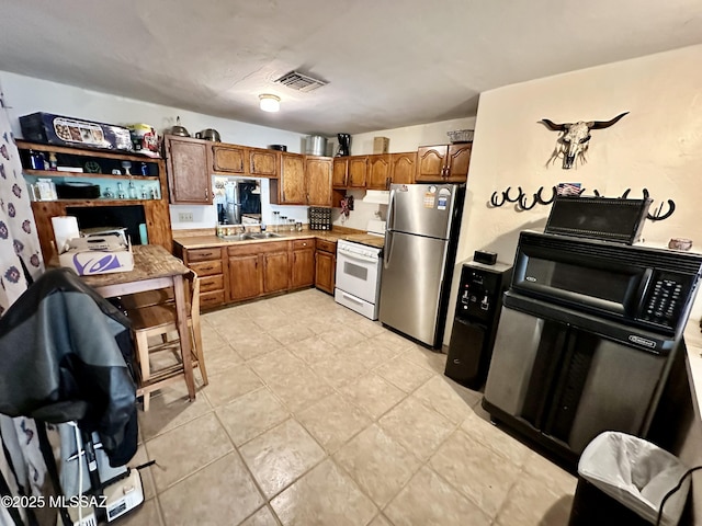 kitchen with white range, light countertops, visible vents, freestanding refrigerator, and a sink