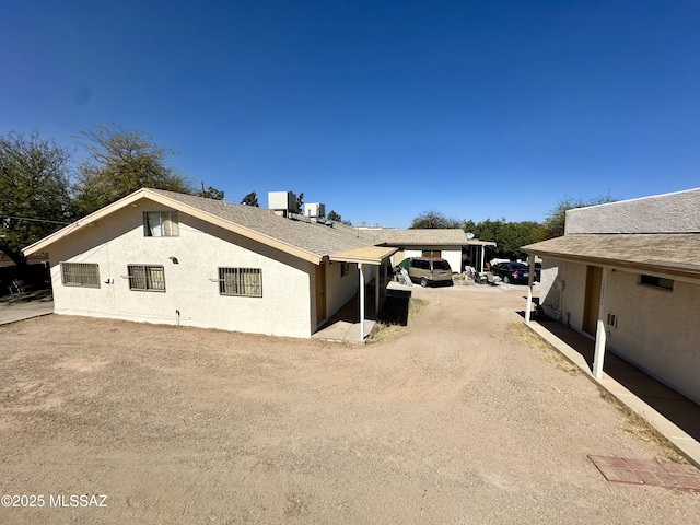 view of side of property with dirt driveway and stucco siding